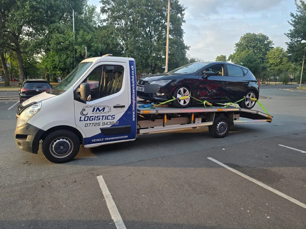 Damaged black SEAT Leon on IM Logistics flatbed — 24/7 accident recovery