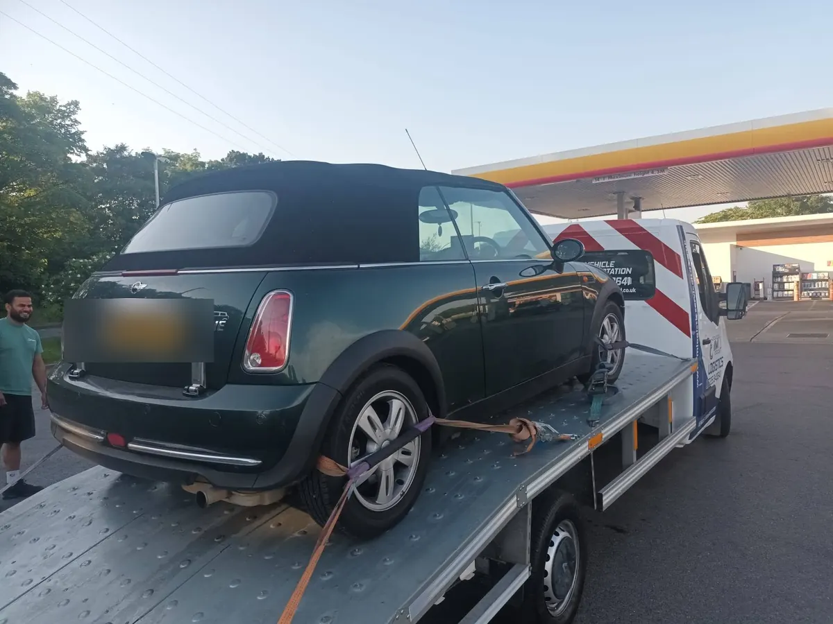 Dark green Mini One convertible on IM Logistics flatbed — car recovery, day and night